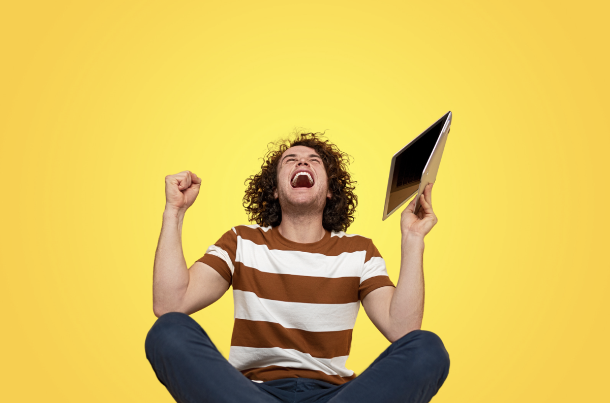 man cheering with laptop in his hand